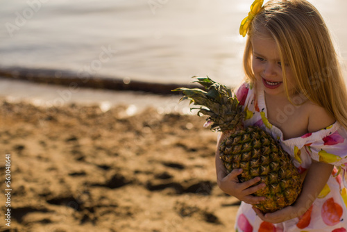 close uphappy little girl with pineapple near the sea summertime photo