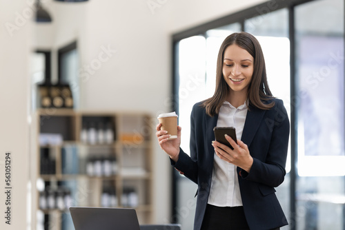 Smiling businesswoman using phone in office. Small business entrepreneur looking at her mobile phone and smiling © Natee Meepian