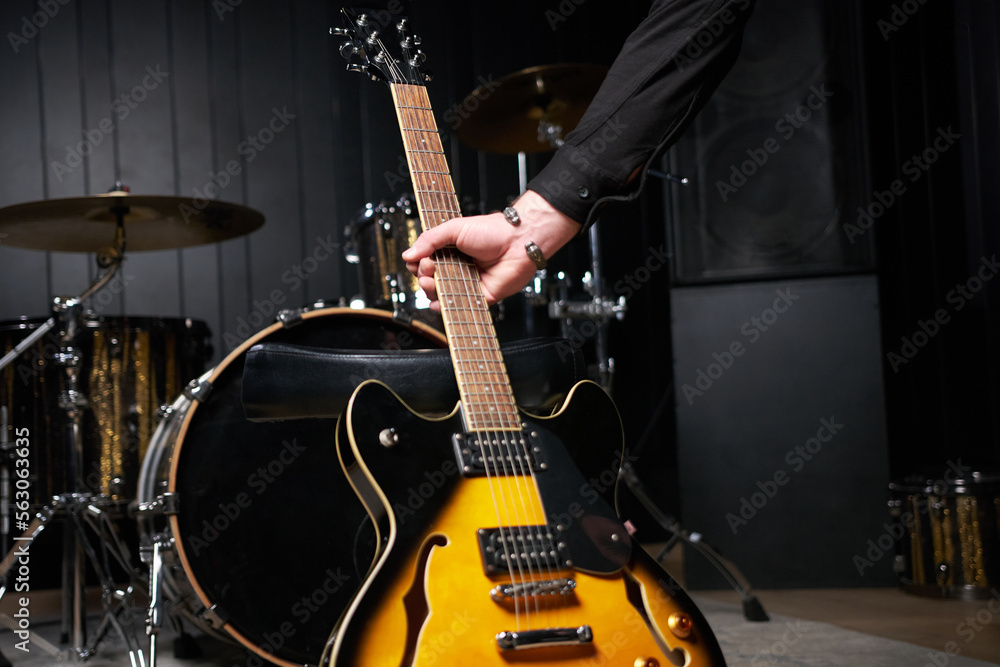 Fototapeta premium Guitarist man takes out electric guitar of the frame Close-up at studio