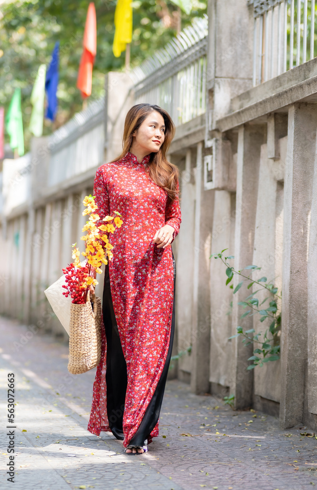 Vietnamese girl with Ao Dai dress walking on street, Ho Chi Minh city, Vietnam. Ao dai is famous traditional costume for woman in Vietnam. Tet holiday and New Year.