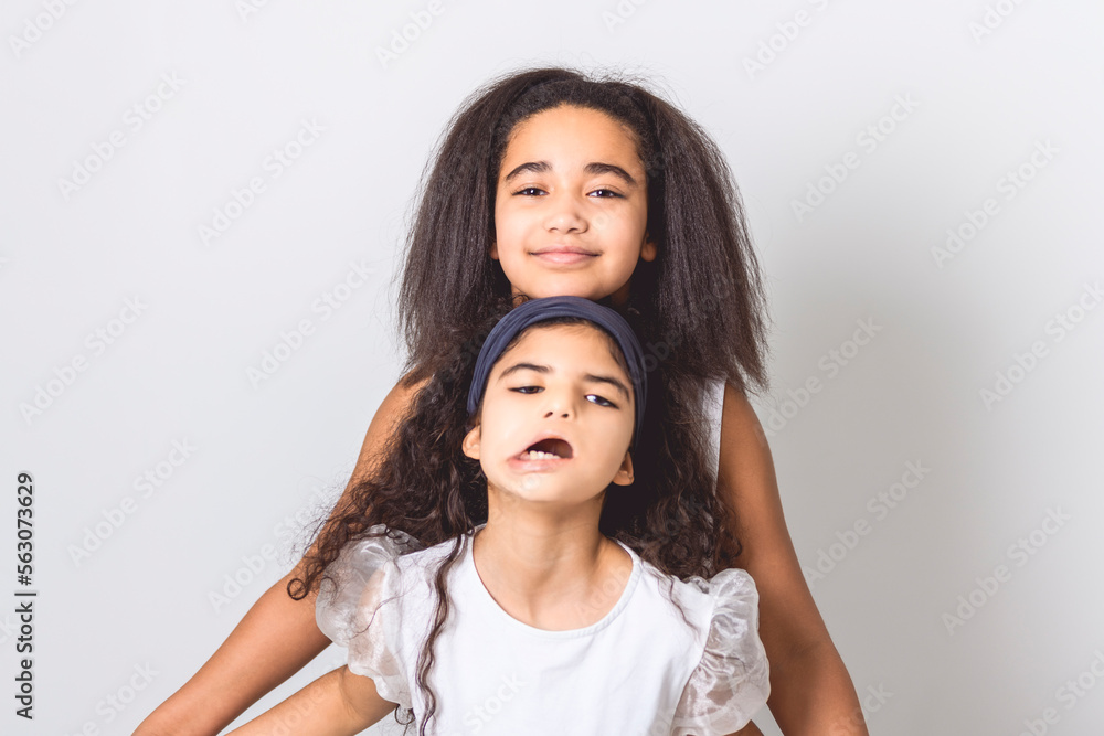 Adorable 9 years child girl on studio white background with her sister Adorable 9 years child girl on studio white background with her sister