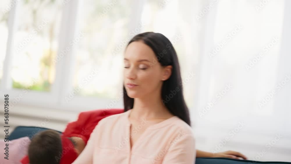 Young woman meditating with her son running around in a superhero costume Young woman meditating with her son running around in a superhero costume