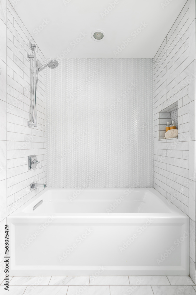 A bright, white shower with subway and herringbone tile lining the shower walls. A bright, white shower with subway and herringbone tile lining the shower walls.