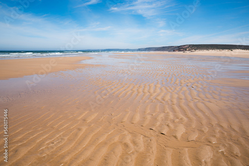 coastal landscape Bordeira beach with rippled sand and cliff at the horizon