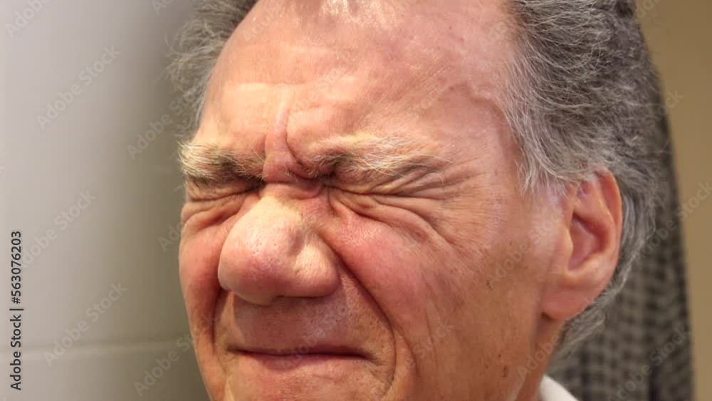 Close up of an older man squinting with both eyes Close up of an older man squinting with both eyes