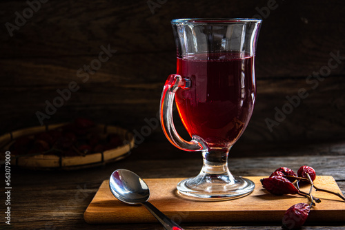 Rosehip tea in a glass cup on a wooden background.