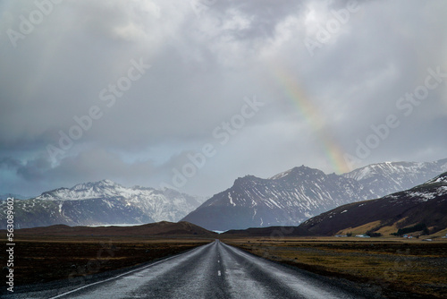 Straight road leading into Icelandic mountains under dramatic skies