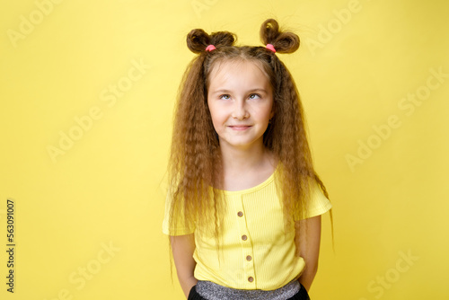 Cool cute girl with a trendy hairstyle in a yellow top on a yellow background with bright emotions