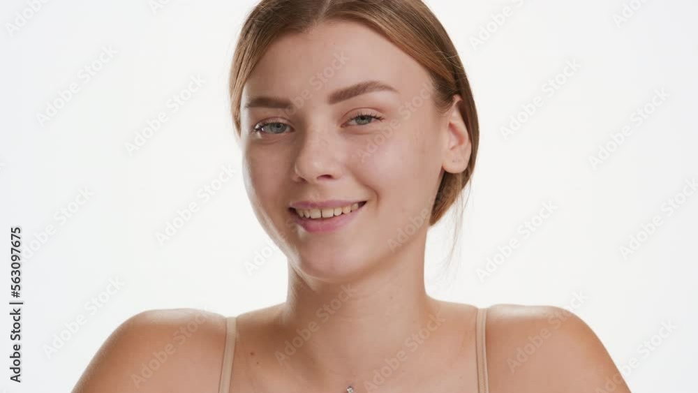 Eye care products commercial | Close-up shot of cute young slim brown-haired Caucasian woman looks aside for a while smiling wide for the camera on white background Eye care products commercial | Close-up shot of cute young slim brown-haired Caucasian woman looks aside for a while smiling wide for the camera on white background
