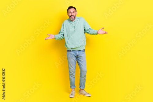 Full length photo of funky man wear trendy clothes raise hands show no answer sorry stand empty space isolated on yellow color background