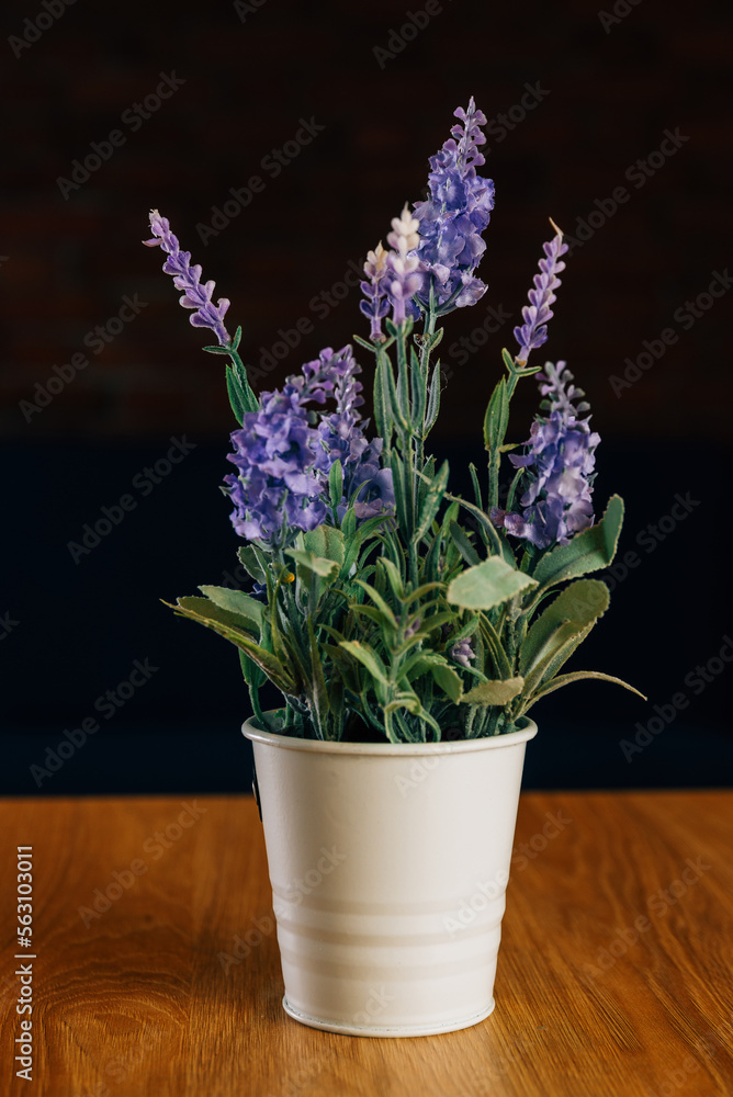 Vertical shot of some violet artificial lavender flowers standing on a wooden table. Vertical shot of some violet artificial lavender flowers standing on a wooden table.