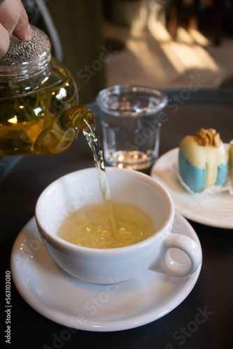Green tea in transparent teapots, tea in a cup and macaroons on a plate