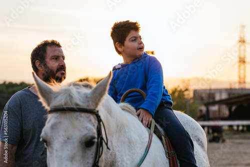 Boy with cerebral palsy and therapist in equine therapy session