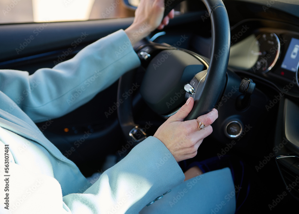 Close-up of female driver's hands on the steering wheel of modern comfortable automobile while driving car in city road. Car insurance policy. People. Urban lifestyle and Safety driving concept
