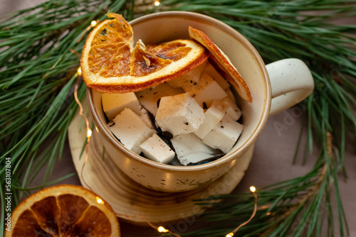 Marshmallows in a cup, dried orange and Christmas tree branches near the cup