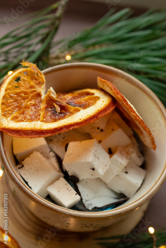 Marshmallows in a cup, dried orange and Christmas tree branches near the cup