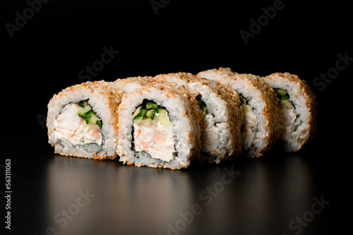 Tasty sushi rolls california with snow crab, cream cheese, cucumber, sesame seeds on dark background. photo