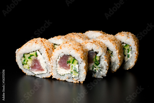 Sushi rolls california with salmon, cream cheese, cucumber, sesame seeds on dark background.