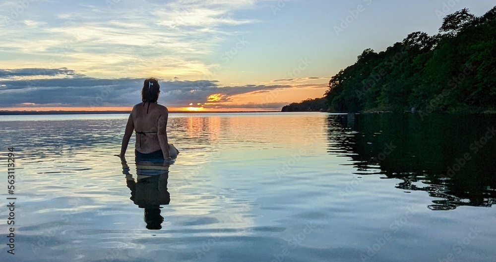 femme coucher de soleil flottant sur l'eau.