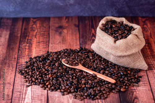 coffee beans on wooden table and wooden spoon with blue background out of focus