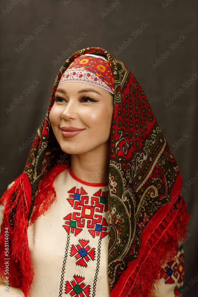 Fototapeta premium a girl in a Chuvash dress and with a red scarf on a dark background