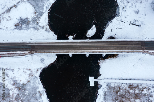 Old stone bridge over the river on a snowy winter day, top down view photo