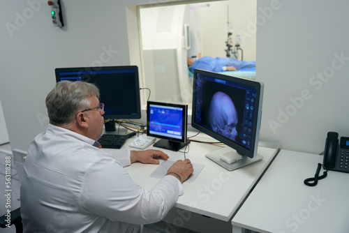 Experienced doctor sits in front of monitors of diagnostic equipment