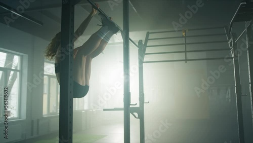 CrossFit sportswoman performing kipping pull-ups. Determined female athlete working out with her own weight at the gym. High quality 4k footage photo