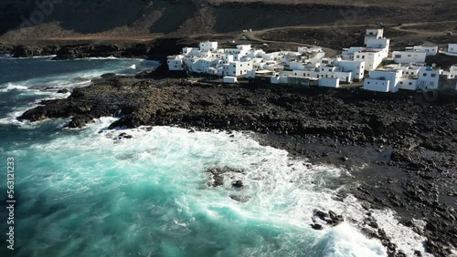 One of Lanzarote's less-known coastal towns, Tenesar is truly a beautiful little spot to appreciate Lanzarote's western coast - Drone arial view of white village houses and sae storm with waves surf  photo