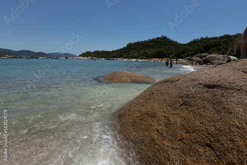 Clear water beach with rocks and mountaisn on an island photo