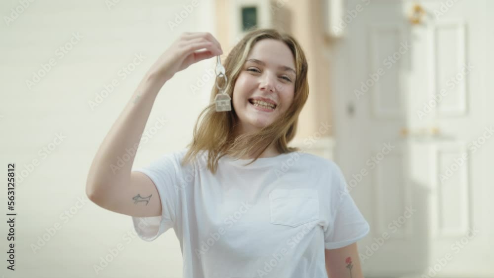 Young caucasian woman smiling confident holding key of new home at street Young caucasian woman smiling confident holding key of new home at street