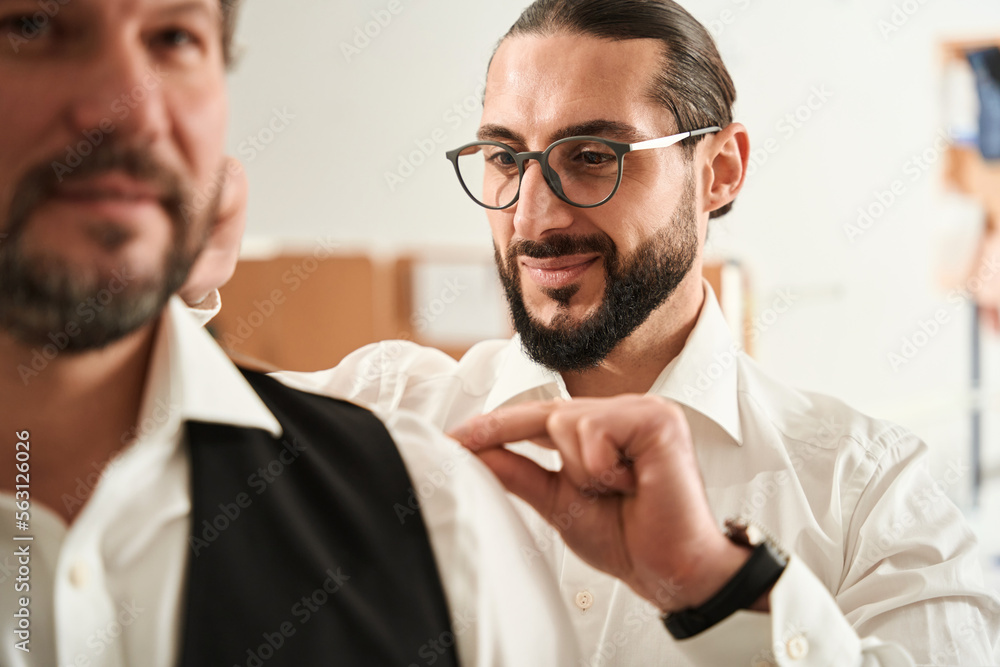 Pleased young fashion designer measuring male client Pleased young fashion designer measuring male client