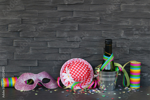 Party und Karneval Hintergrund mit Luftschlangen, Maske, Konfetti, Sekt,und Hut vor einer Mauer mit Platz für Text. photo