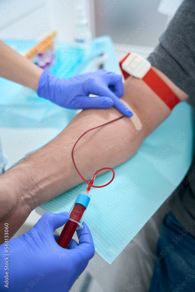 Nurse takes a blood sample from vein from a patient Nurse takes a blood sample from vein from a patient