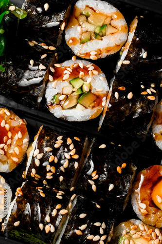 Close-up top view on kappa maki sushi rolls drizzled with soy sauce and sesame seeds