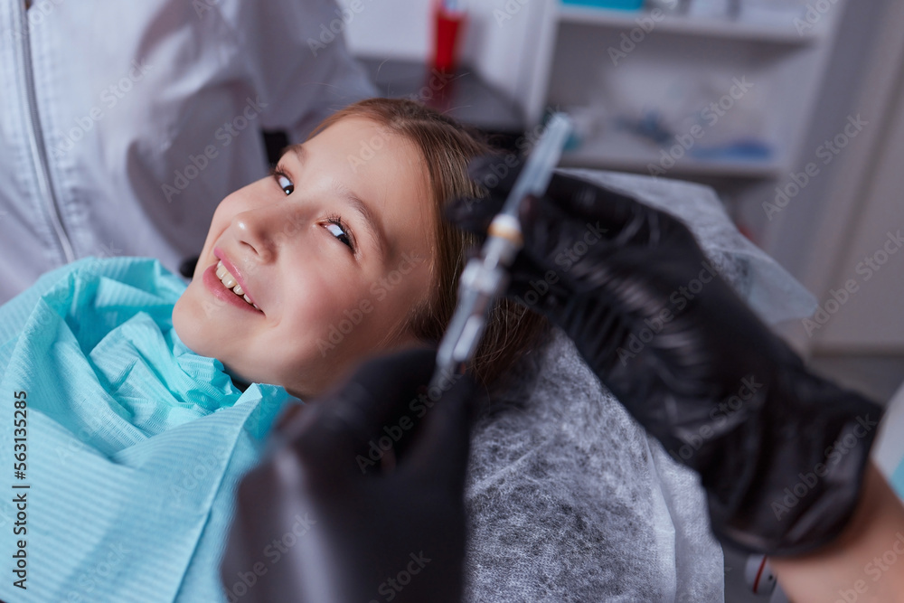 Little girl at dentist office, getting local anesthesia injection into