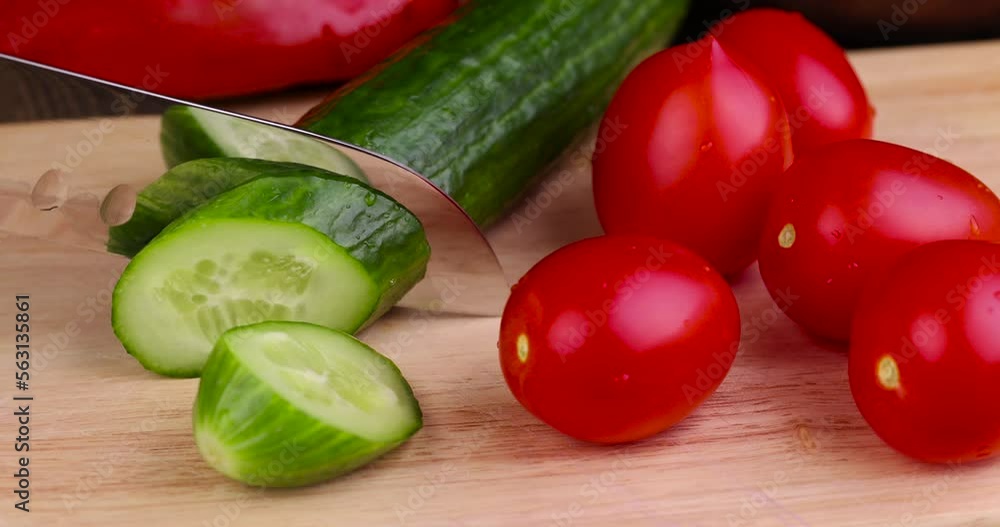 Slice a green ripe cucumber in thin circles, washed a long green cucumber during slicing for salad Slice a green ripe cucumber in thin circles, washed a long green cucumber during slicing for salad