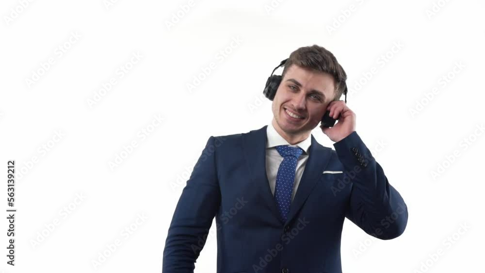 A male businessman in a suit and tie with headphones on his head dances and listens to music. On a white background. A male businessman in a suit and tie with headphones on his head dances and listens to music. On a white background.