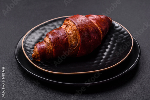Delicious crispy croissant with chocolate on a black ceramic plate
