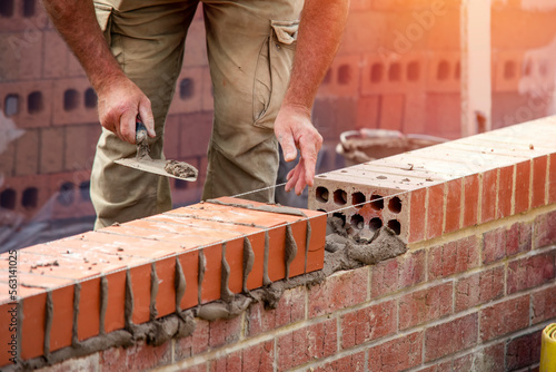 Tableau sur toile Industrial bricklayer laying bricks on cement mix on construction site
