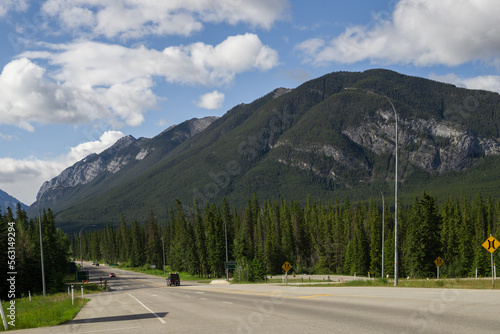 Tourism in the mountains - a road in the forest between the mountains. Great view, summer vacation, Banff, Alberta, Canada