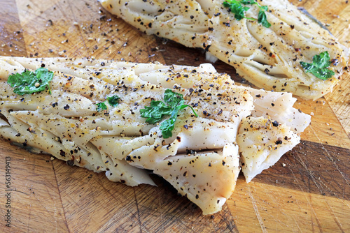 Photography flaky white cod fillets seasoned with salt and black pepper.