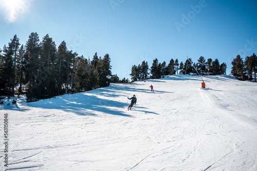 Two boys skiing down a large ski slope.