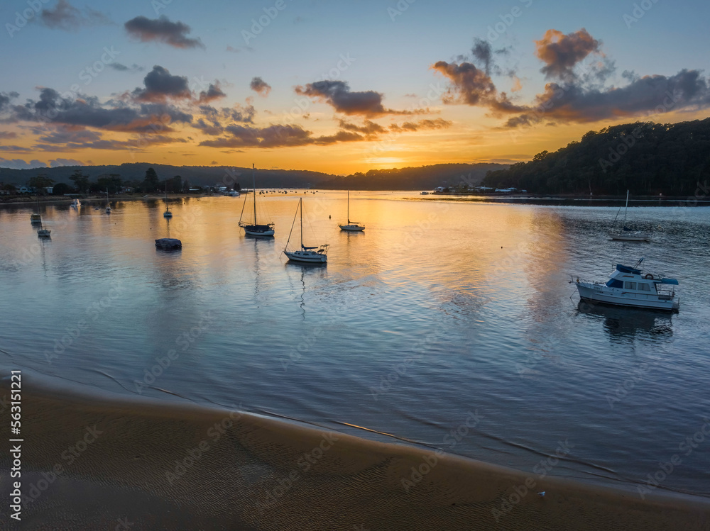 Fototapeta premium Aerial sunrise waterscape with boats and scattered clouds