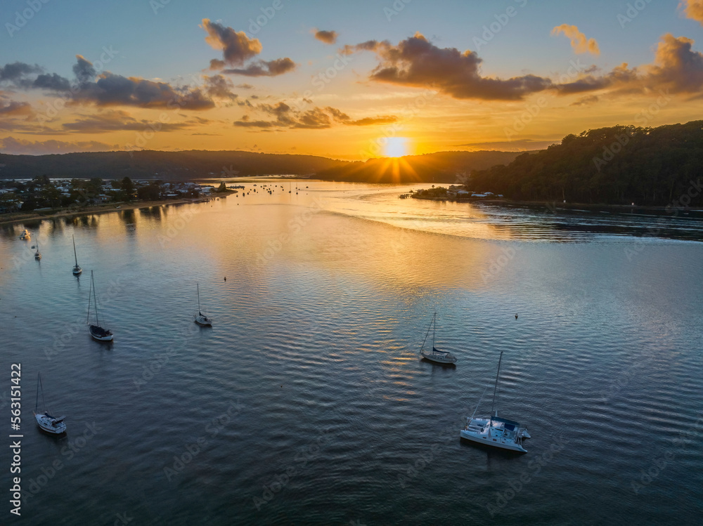 Fototapeta premium Aerial sunrise waterscape with boats and scattered clouds