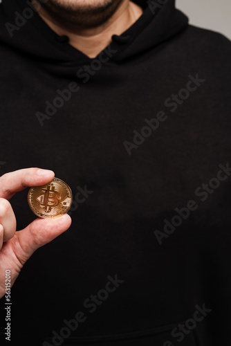 Crypto investor is holding gold bitcoin close-up. Golden Bitcoin coin in hands on black background.