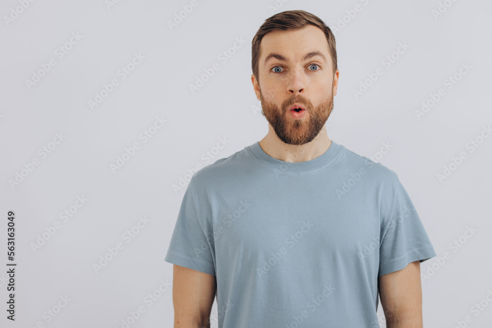 Portrait of a modern bearded middle-aged man in a blue t-shirt showing emotions on a white background Portrait of a modern bearded middle-aged man in a blue t-shirt showing emotions on a white background