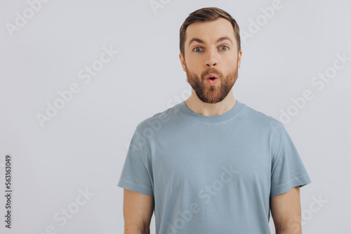 Portrait of a modern bearded middle-aged man in a blue t-shirt showing emotions on a white background