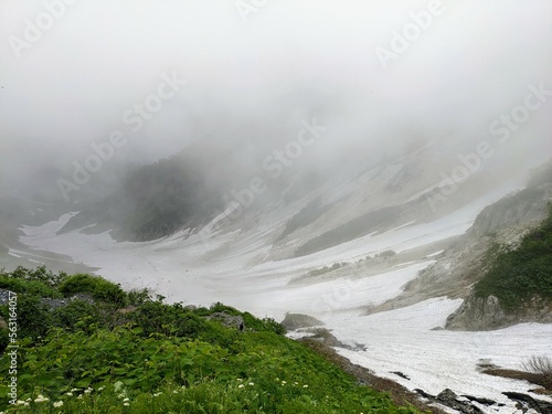 Overlooking Daisekkei, the large snowy valley with fog of Mt. Shirouma in July. Hakuba Village, Nagano Prefecture, Japan photo