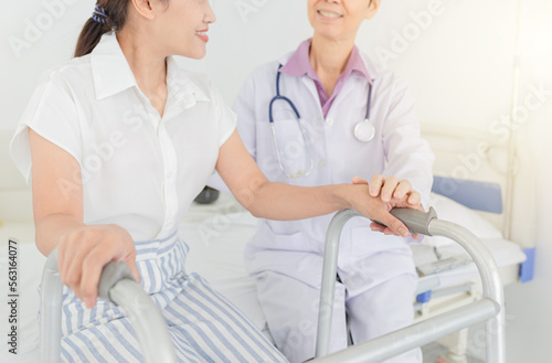 Asian doctor explaining to female patient about how to use walker, she assessment symptom of patient, walk training and rehabilitation process 